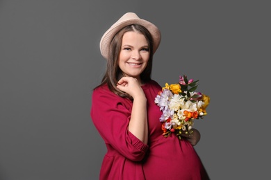 Photo of Beautiful pregnant woman with flowers on color background