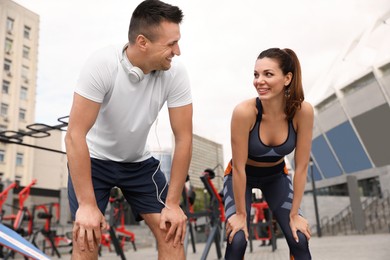Photo of Woman and man in fitness clothes resting near outdoor gym
