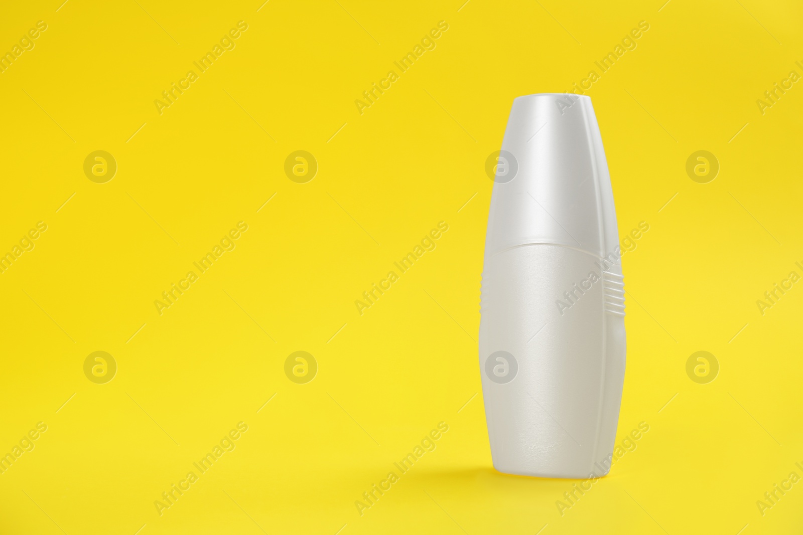 Photo of Bottle with insect repellent spray on yellow background, space for text