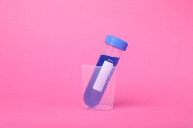 Photo of Beaker with test tube and liquid on bright pink background. Kids chemical experiment set