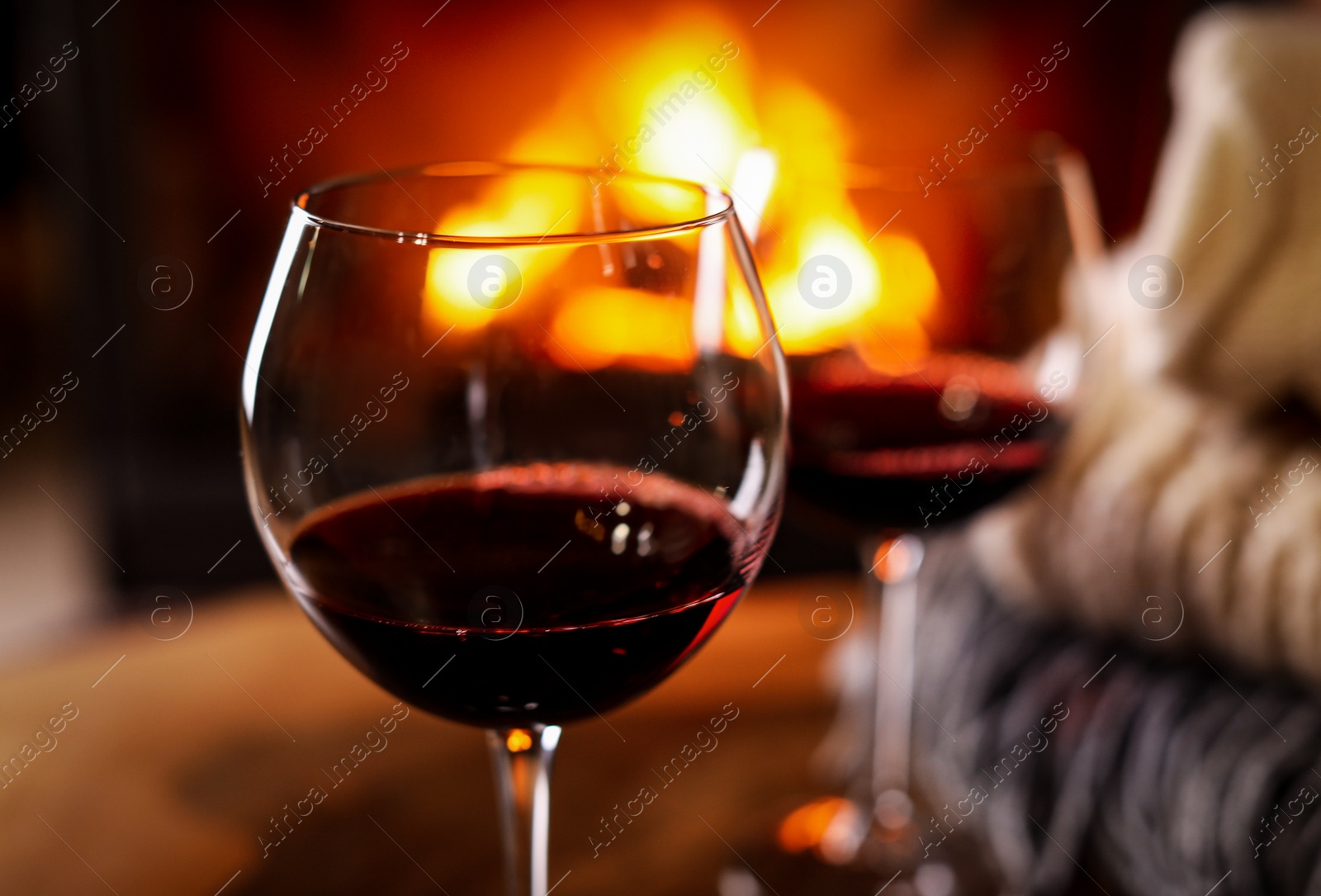 Photo of Glasses of wine, knitwear and blurred fireplace on background