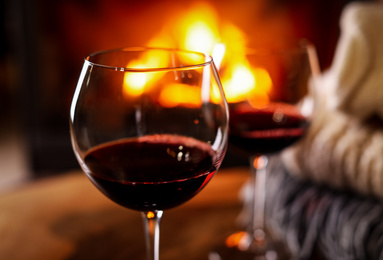 Photo of Glasses of wine, knitwear and blurred fireplace on background