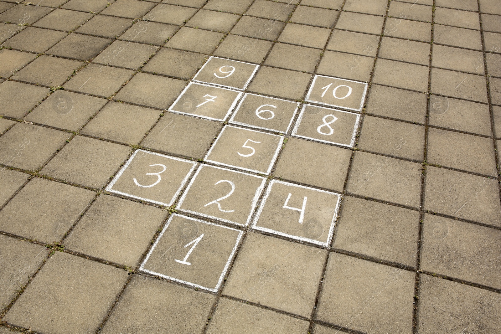 Photo of Hopscotch drawn with white chalk on street tiles outdoors