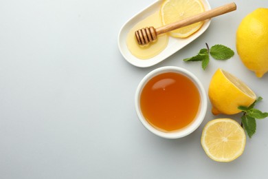 Photo of Sweet honey and fresh lemons on white table, flat lay. Space for text
