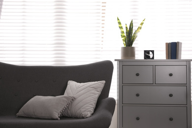 Photo of Stylish living room interior with comfortable sofa and cabinet near window