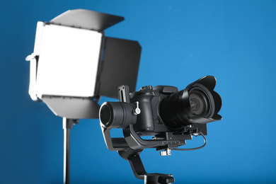 Photo of Professional video camera and lighting equipment on blue background