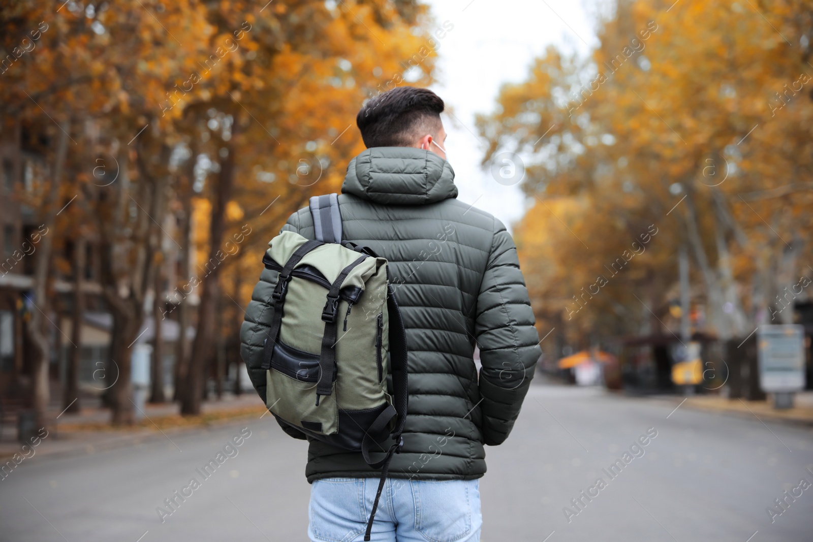Photo of Male tourist with travel backpack on city street, back view. Urban trip