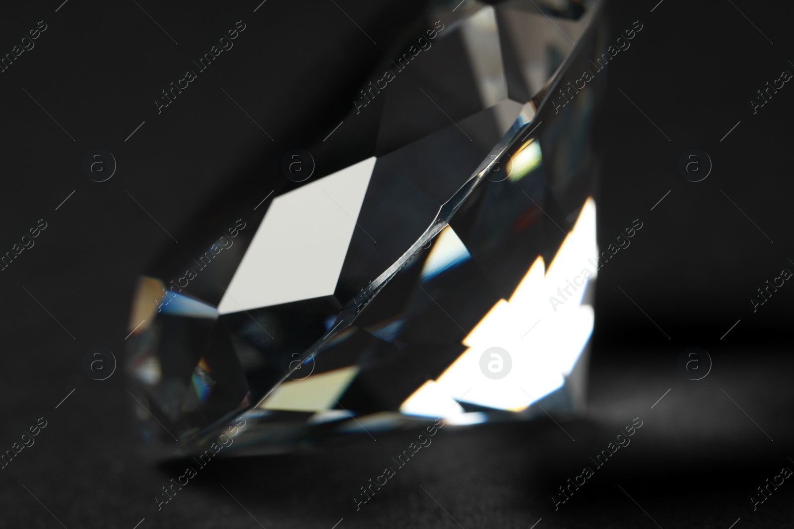 Photo of Beautiful dazzling diamond on dark background, closeup. Precious gemstone