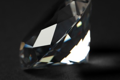 Beautiful dazzling diamond on dark background, closeup. Precious gemstone