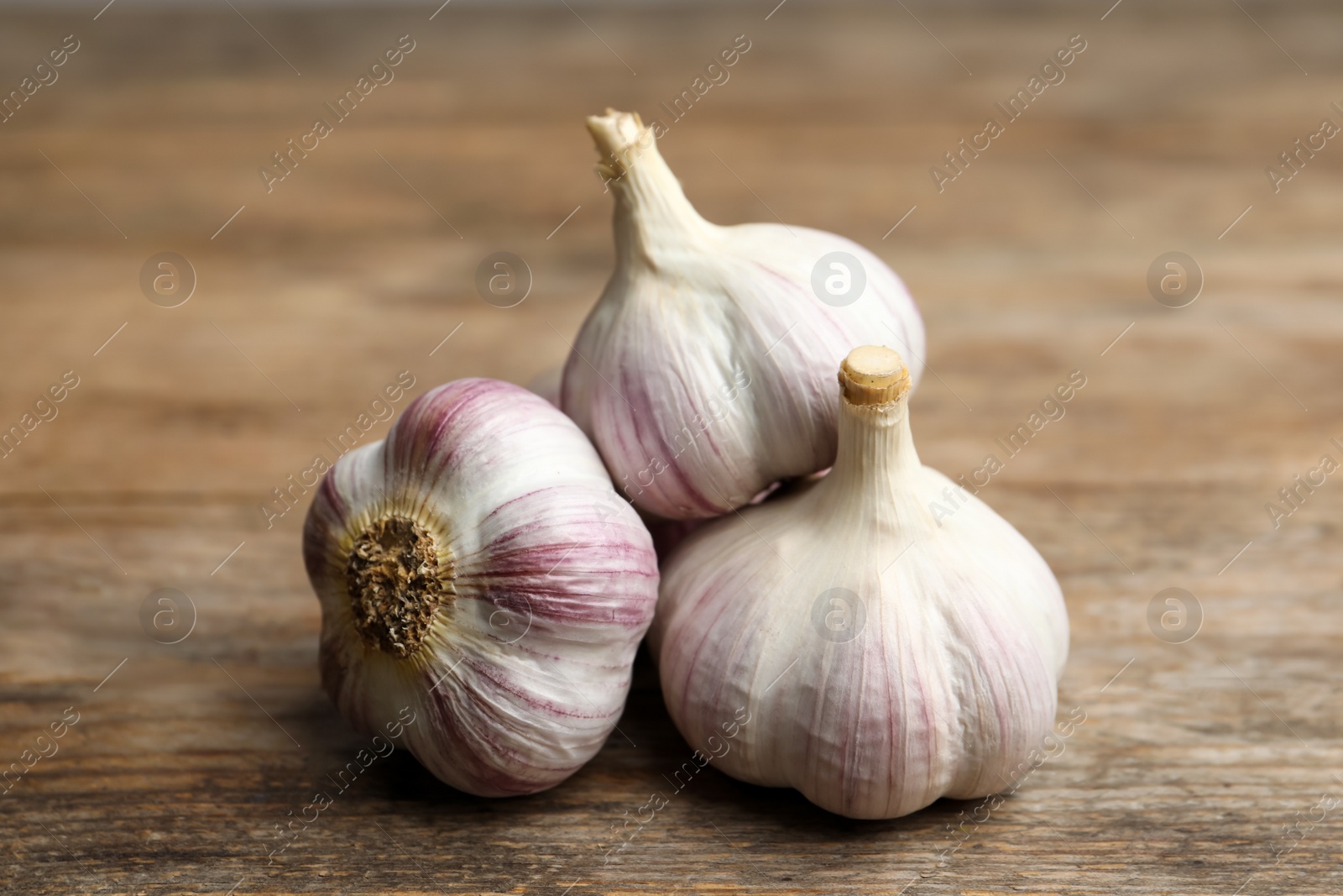 Photo of Fresh organic garlic on wooden table, closeup