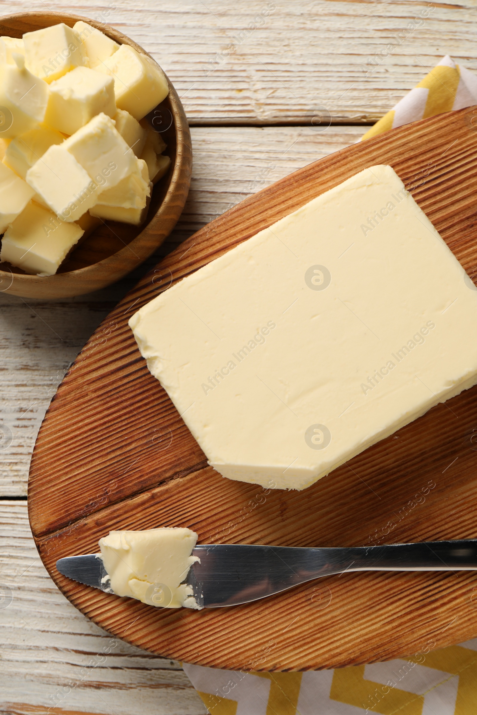 Photo of Tasty butter and knife on light wooden table, top view