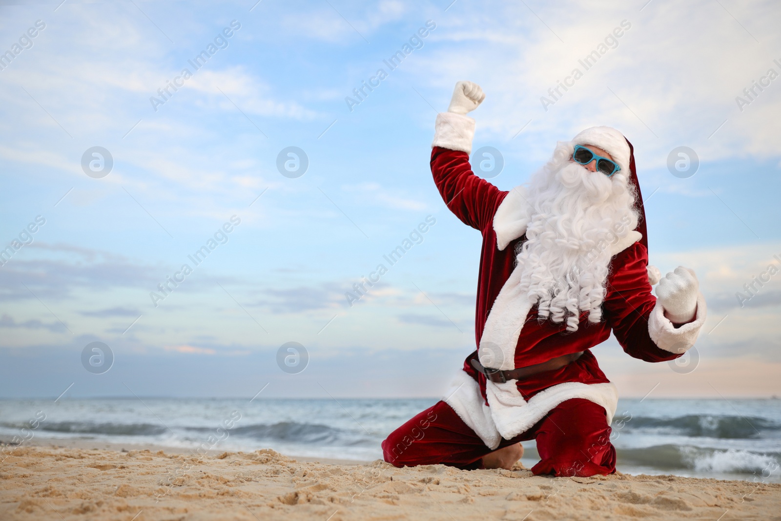 Photo of Santa Claus having fun on beach, space for text. Christmas vacation