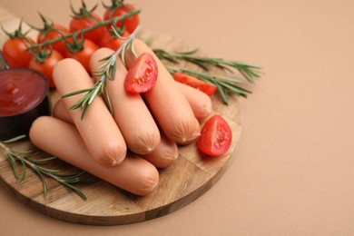 Photo of Delicious boiled sausages, tomato sauce, tomatoes and rosemary on beige table, closeup. Space for text