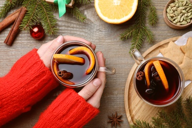 Woman with cup of mulled wine at wooden table, top view