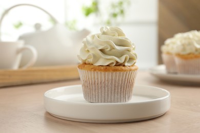 Photo of Tasty cupcake with vanilla cream on light wooden table, closeup