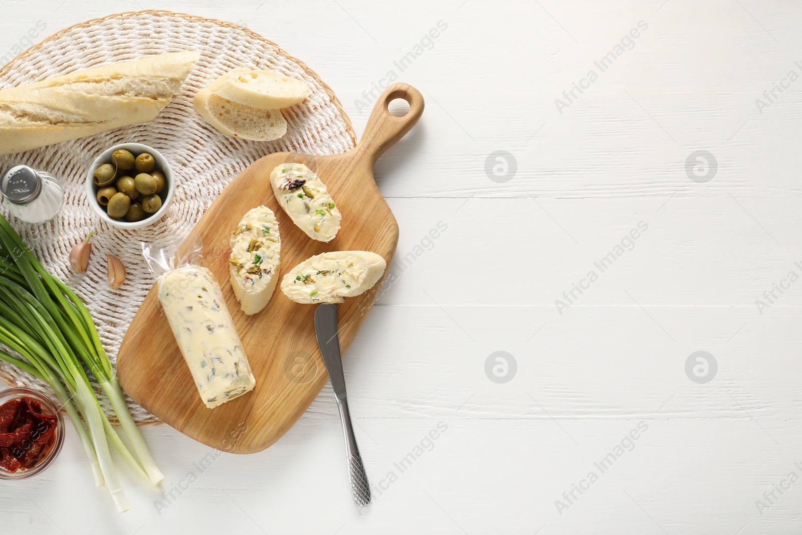 Photo of Tasty butter, bread and other ingredients on white wooden table, top view. Space for text