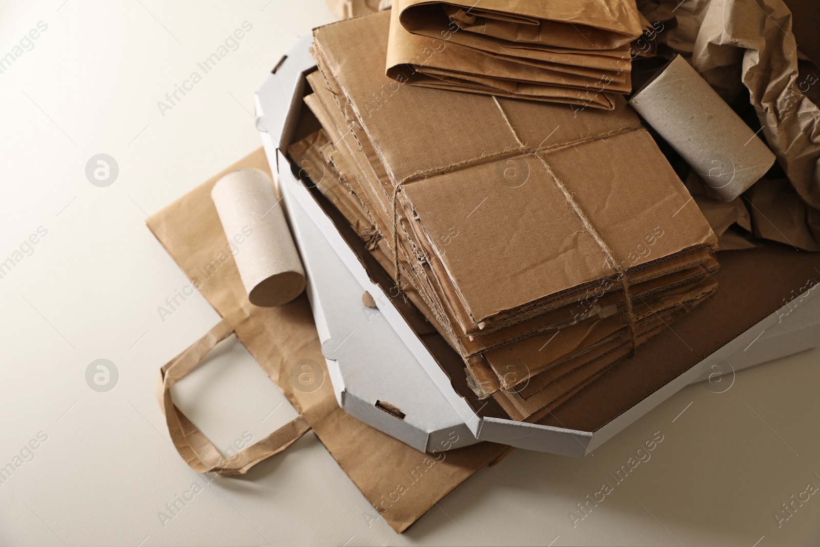 Photo of Stack of different waste paper on beige background, closeup