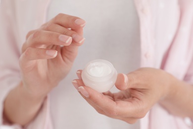 Woman holding open jar with cream, closeup