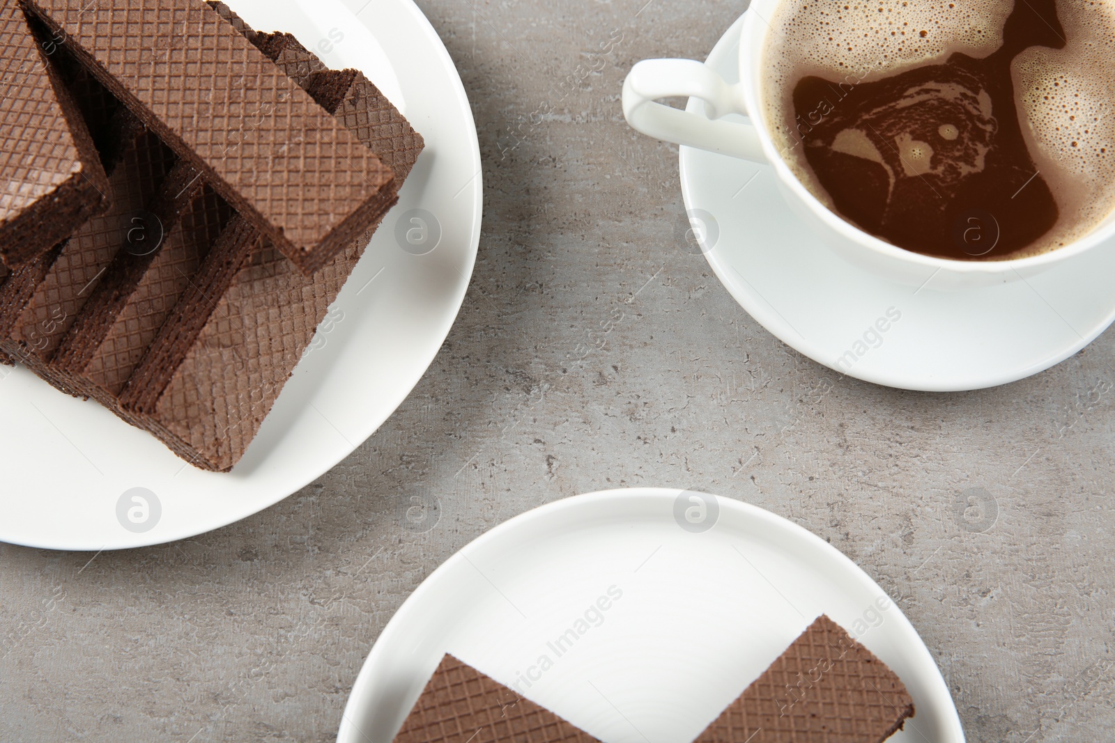 Photo of Delicious chocolate wafers with cup of coffee on grey stone background, flat lay