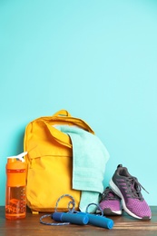 Photo of Sports bag and gym equipment on wooden floor against color background