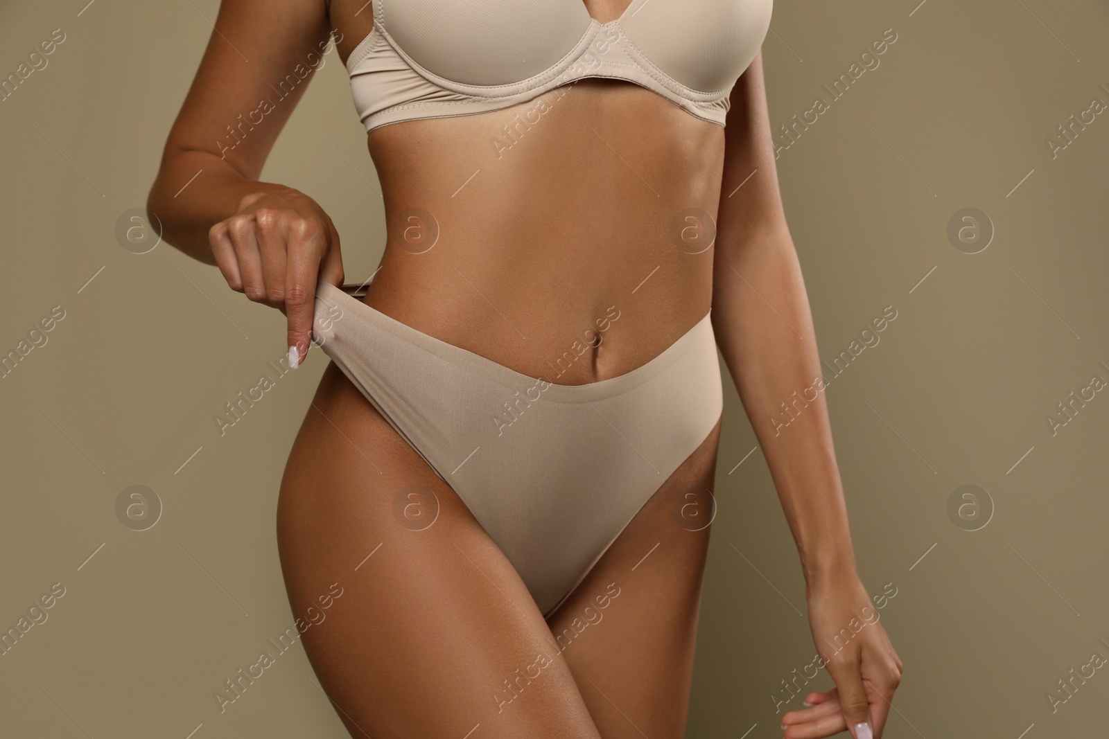 Photo of Woman in panties and bra on beige background, closeup