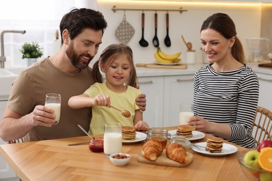 Photo of Happy family having breakfast at table in kitchen