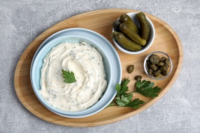 Tasty tartar sauce and ingredients on grey table, top view