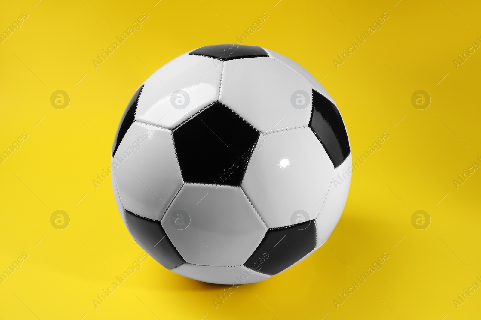 Photo of One soccer ball on yellow background. Sports equipment