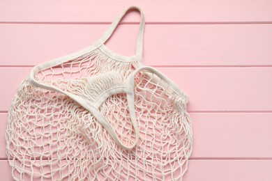 Photo of White string bag on pink wooden table, top view