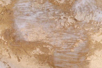 Photo of Texture of golden spray paint as background, top view