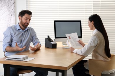 Photo of Human resources manager reading applicant's resume during job interview in office