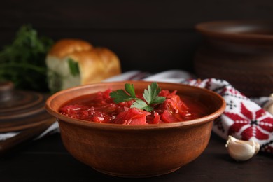 Photo of Stylish brown clay bowl with Ukrainian borsch served on wooden table