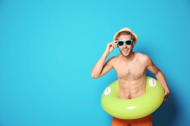 Photo of Young man in shorts with inflatable ring against color background. Space for text