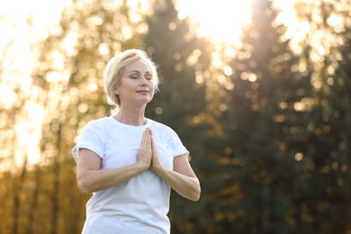 Image of Mature woman practicing yoga outdoors in morning