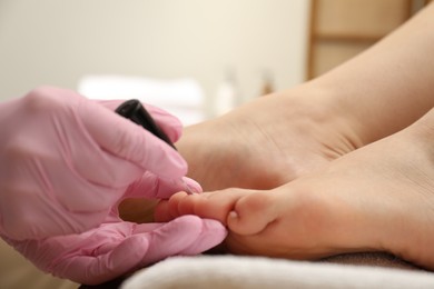 Photo of Professional pedicurist painting client`s toenails with polish in beauty salon, closeup