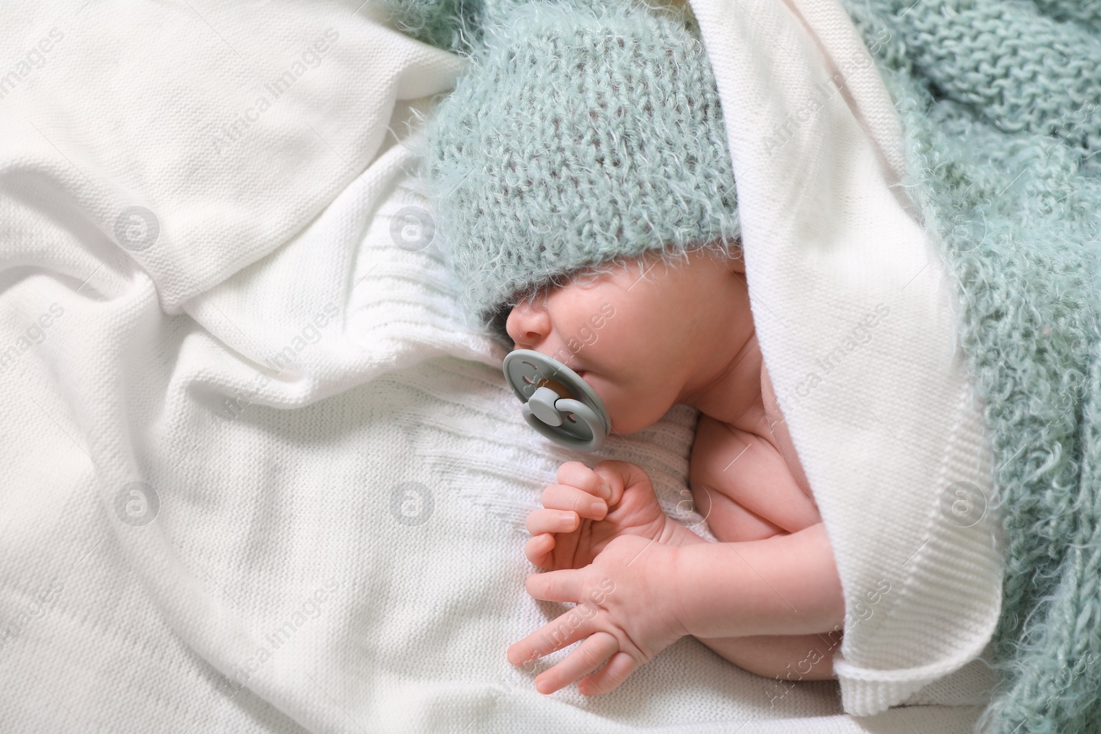 Photo of Cute newborn baby with pacifier sleeping on white blanket, top view. Space for text