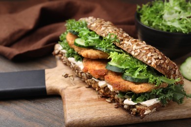 Delicious sandwich with schnitzel on wooden table, closeup