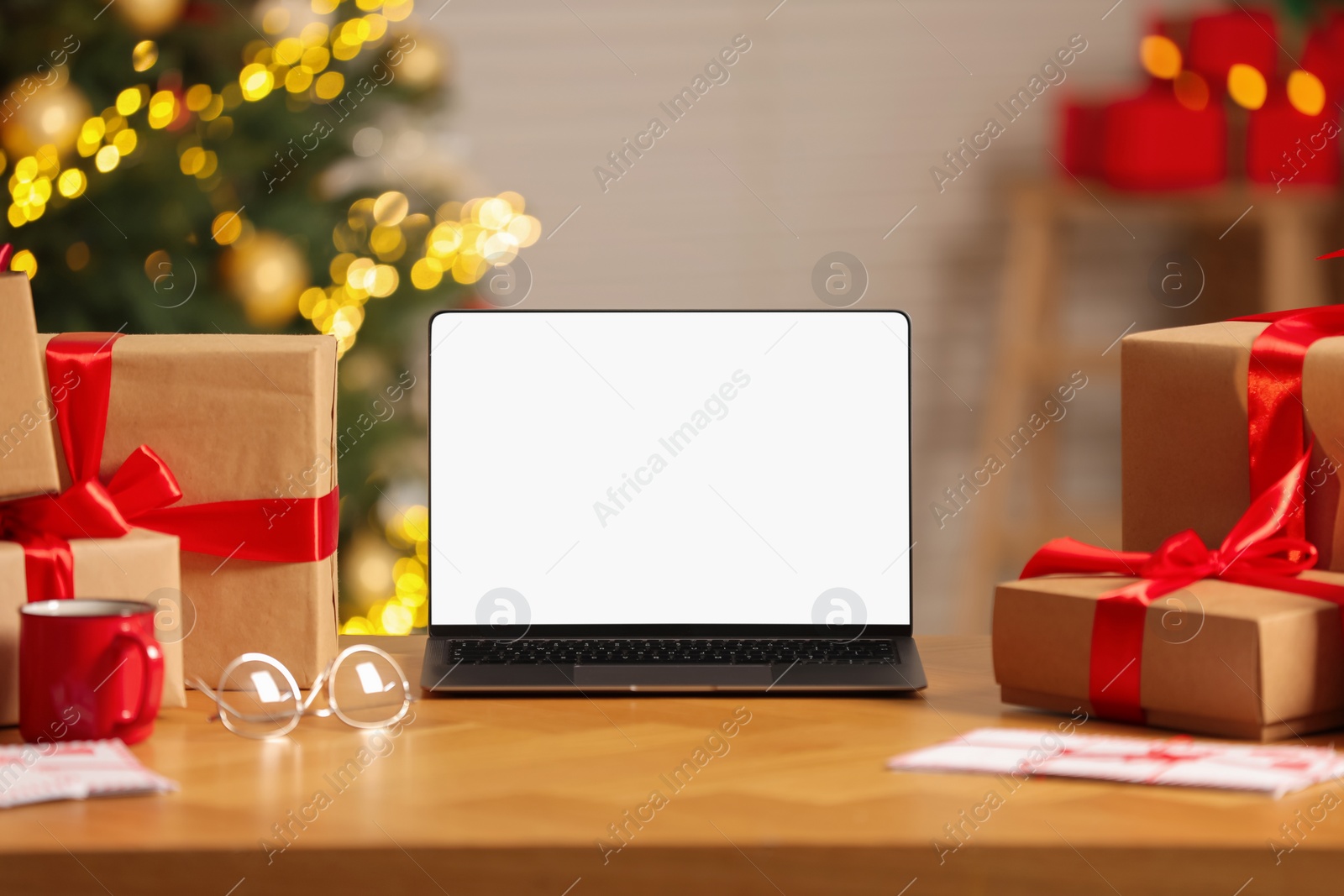 Photo of Laptop with blank screen, Christmas gifts and letters on table at home