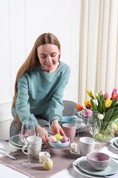 Photo of Woman setting table for festive Easter dinner at home