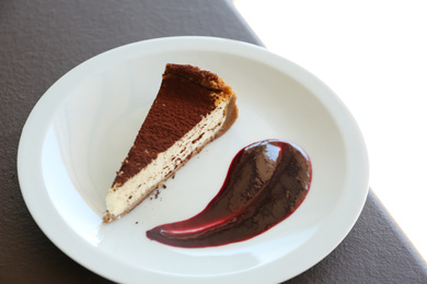 Photo of Slice of delicious cheesecake and raspberry sauce on plate