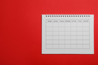 Photo of Blank calendar on red background, top view. Space for text
