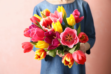 Woman holding beautiful spring tulips on light background, closeup
