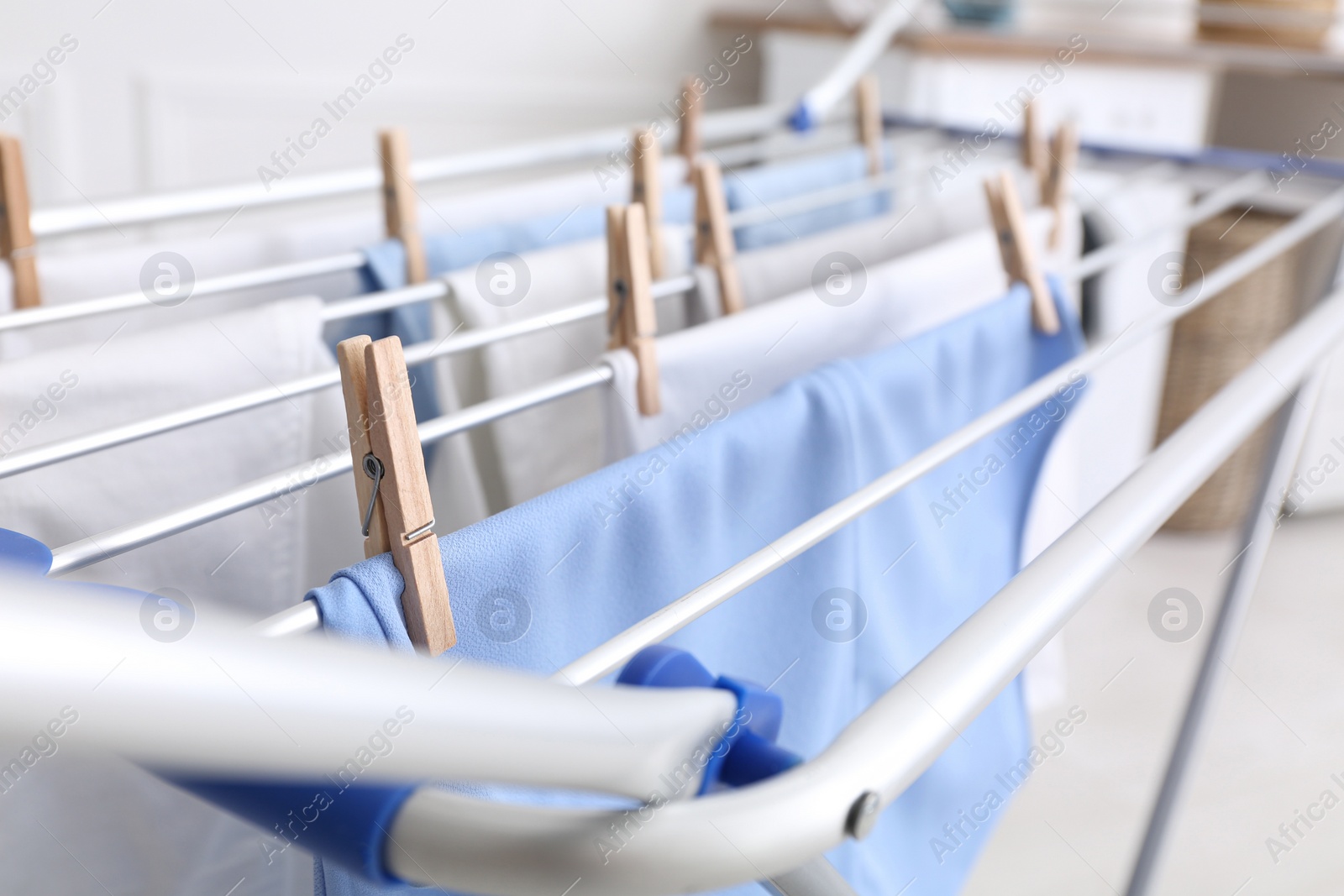 Photo of Clean laundry hanging on drying rack indoors, closeup