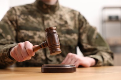 Photo of Law concept. Man in military uniform with gavel at wooden table, closeup