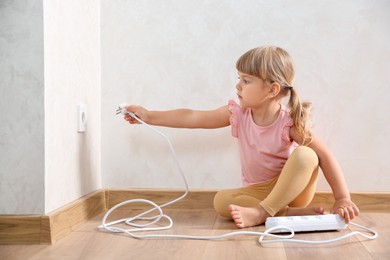 Little child playing with electrical socket and power strip plug at home. Dangerous situation