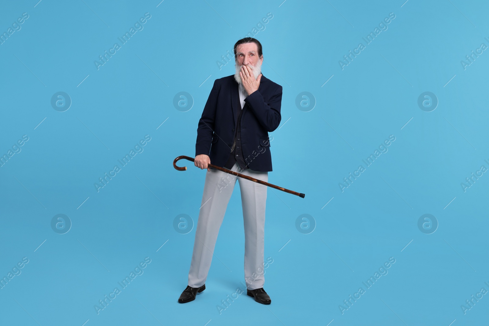 Photo of Surprised senior man with walking cane on light blue background