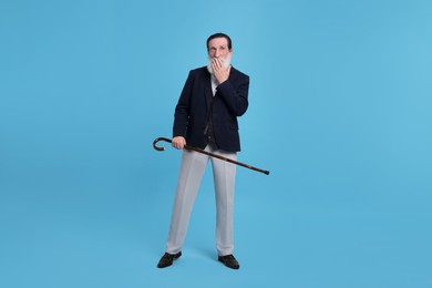 Photo of Surprised senior man with walking cane on light blue background