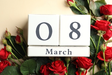 Wooden block calendar with date 8th of March and roses on beige background, flat lay. International Women's Day