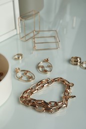 Photo of Stylish golden bijouterie on table, closeup. Elegant jewelry