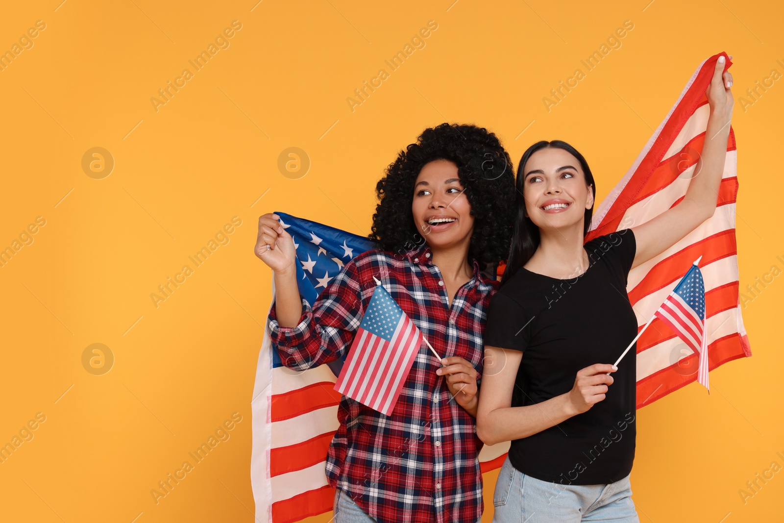 Photo of 4th of July - Independence Day of USA. Happy women with American flags on yellow background. Space for text
